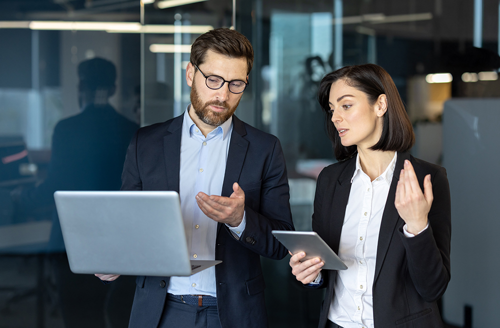 Teammates collaborating on a project using a laptop.