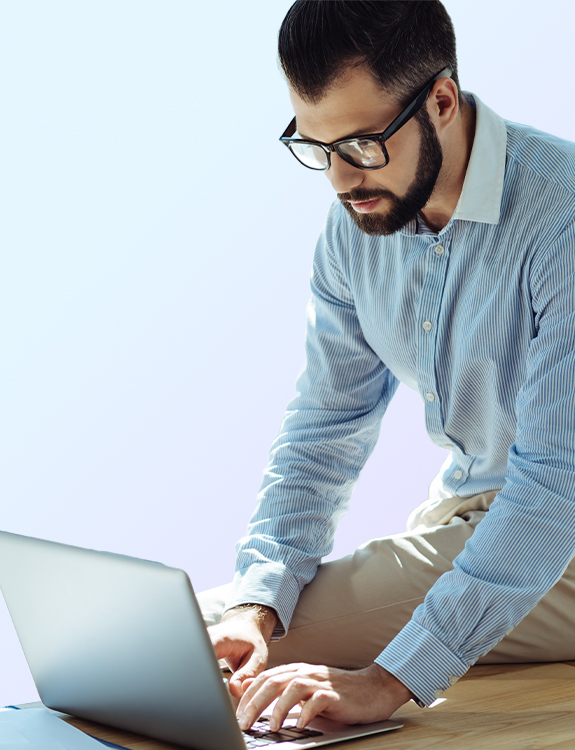 Man sitting on a desk while working on a laptop
