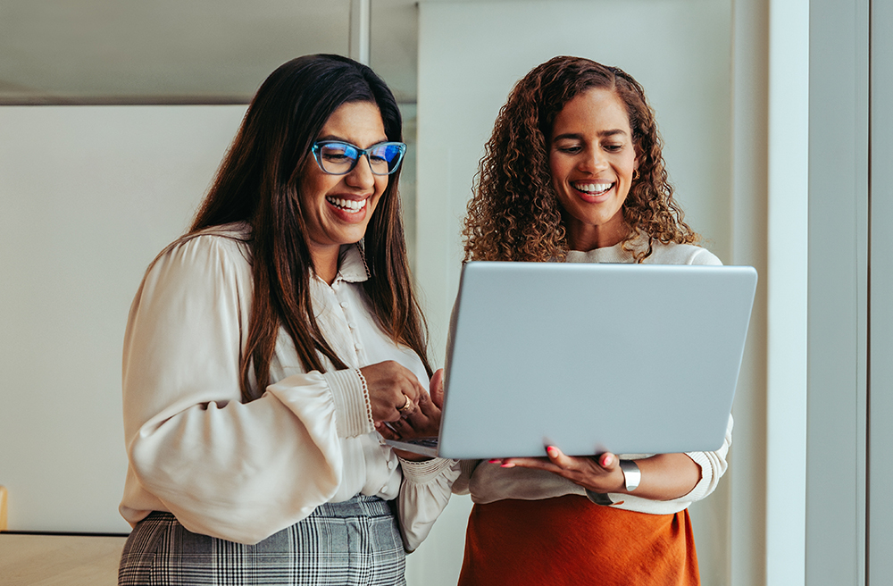 Teammates collaborating on a project using a laptop.