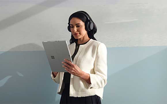 Een vrouw met koptelefoon gerbuikt de Surface Pro 8 