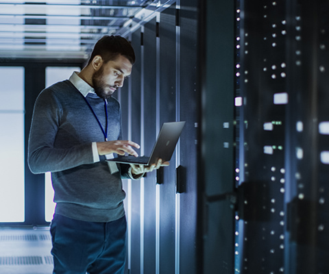 IT professional on a laptop in a server room