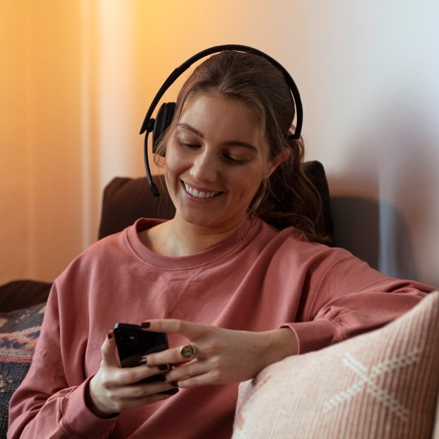 woman with headset on looking at mobile phone at home